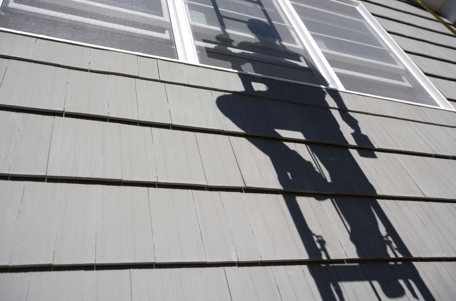 Hausschindeln mit dem Schatten eines Malers auf einer Leiter