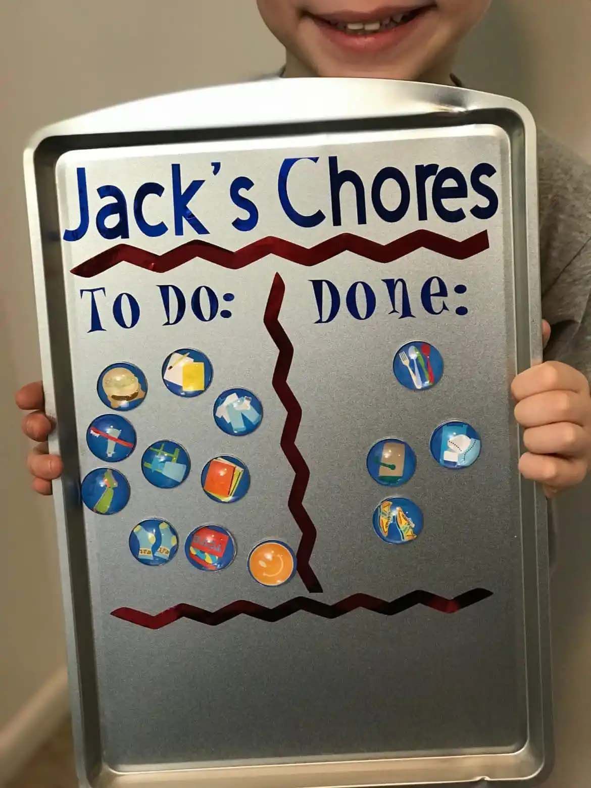 A child holding a magnet chore chart