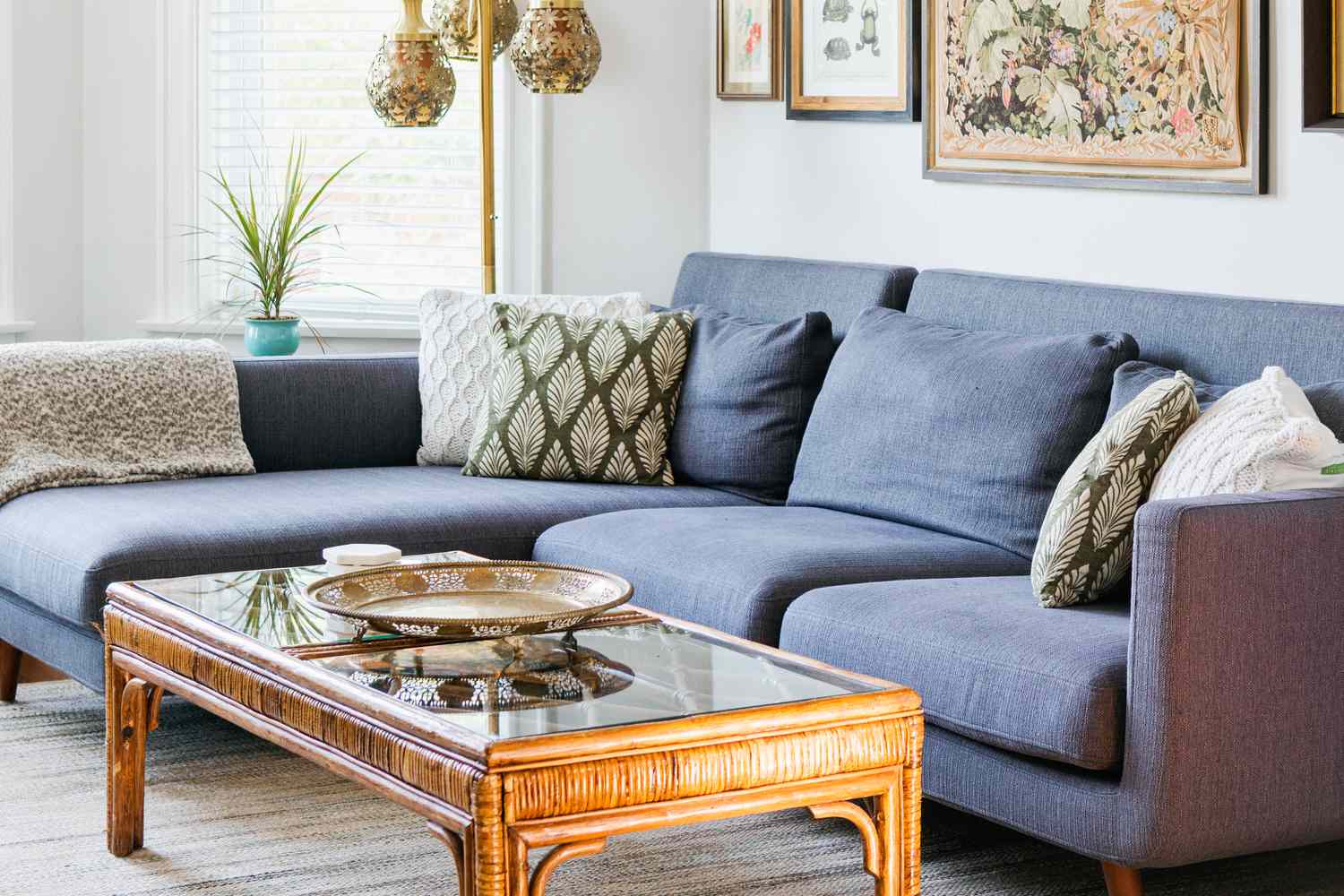 Dekoriertes Wohnzimmer mit marineblauer Couch und Rattan-Couchtisch