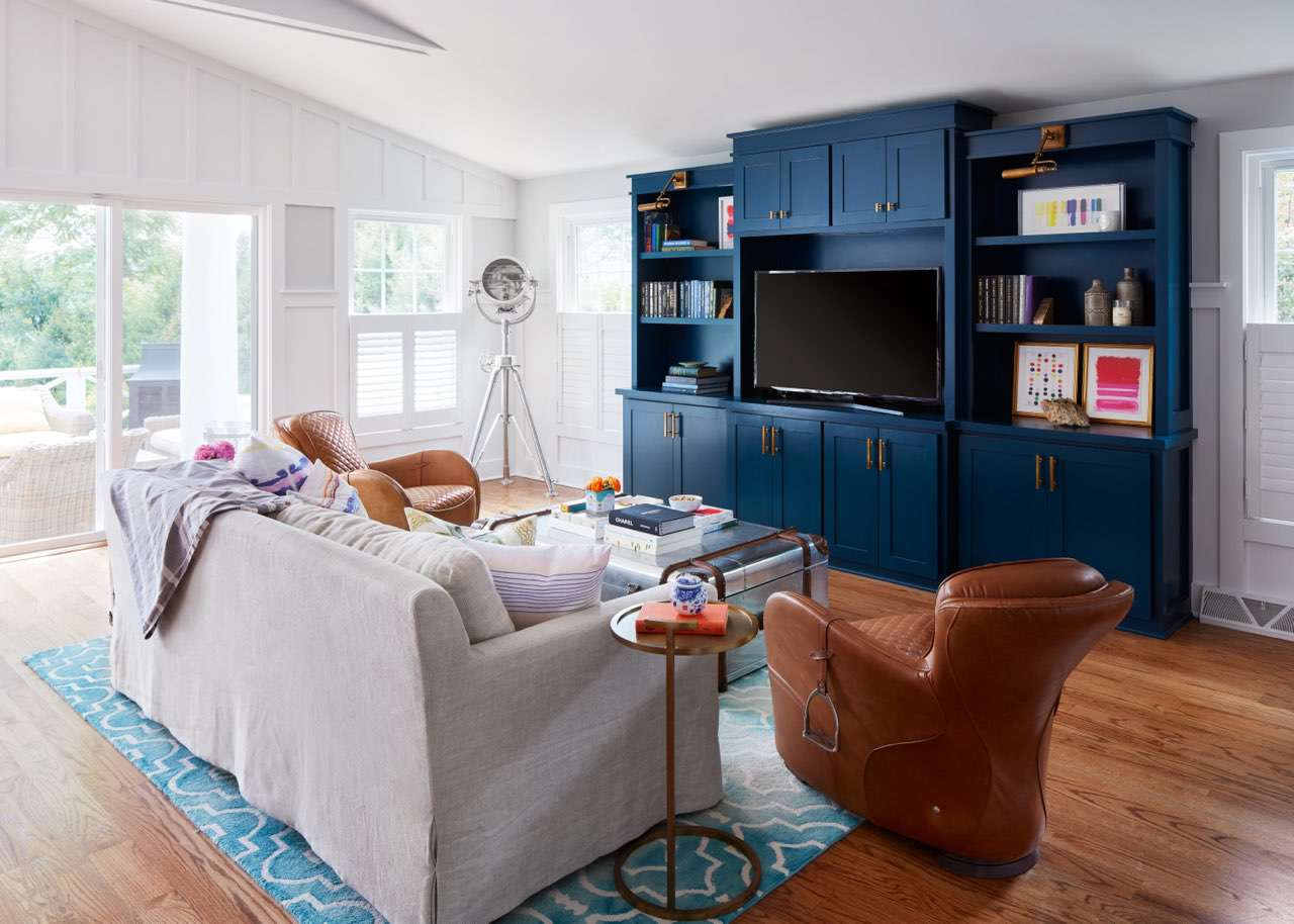 Uma sala de estar com cores neutras como cores principais e toques de marinho e rosa