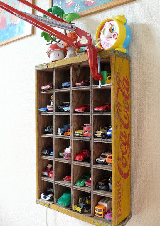 Vintage bottle crate repurposed as toy car storage shelf