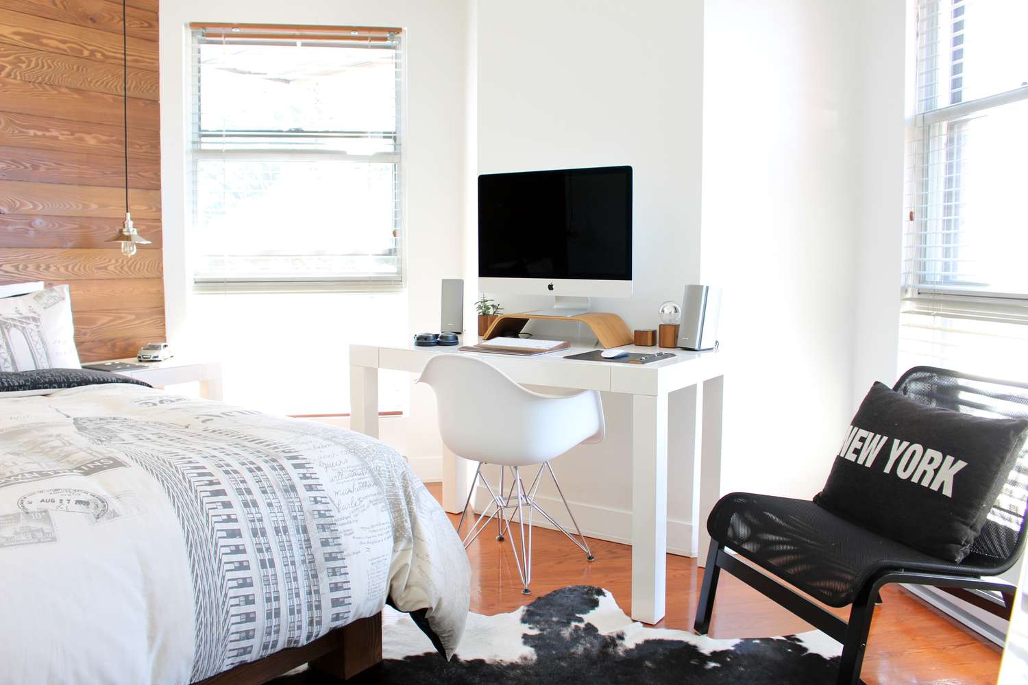 Schlafzimmer mit einer holzgetäfelten Wand und Schreibtisch mit großem Monitor.