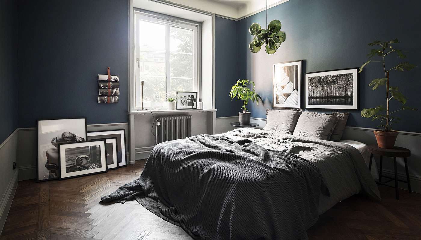 Graue Bettwäsche in einem marineblauen Zimmer.