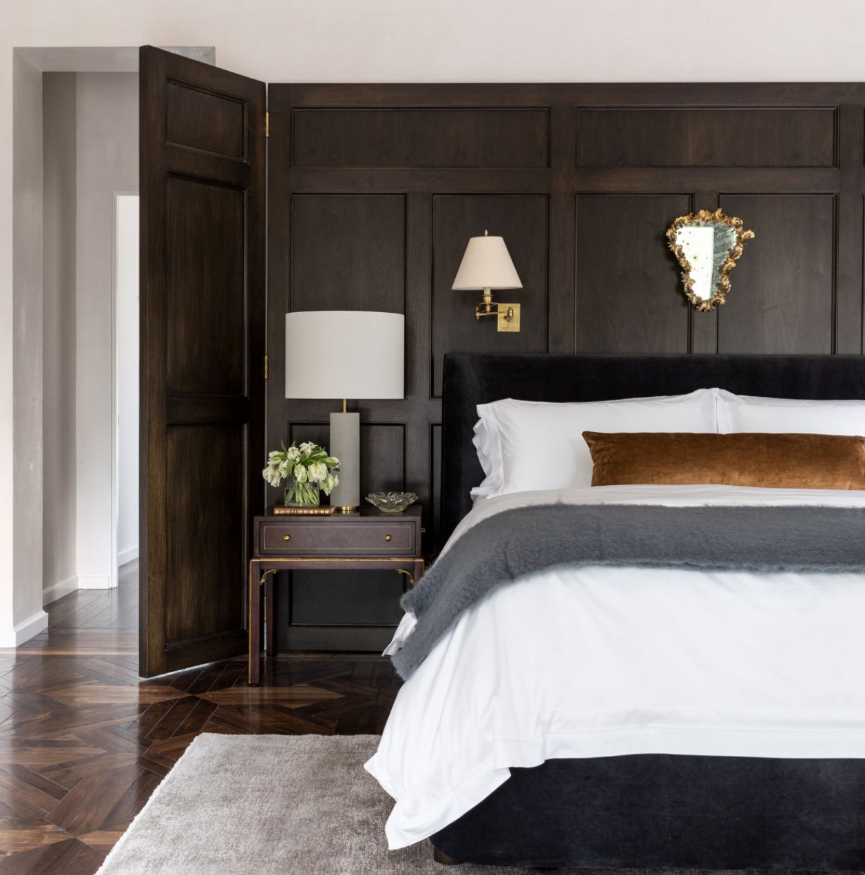 neutral bedroom with wood panel walls, neutral bedding, and wooden floors