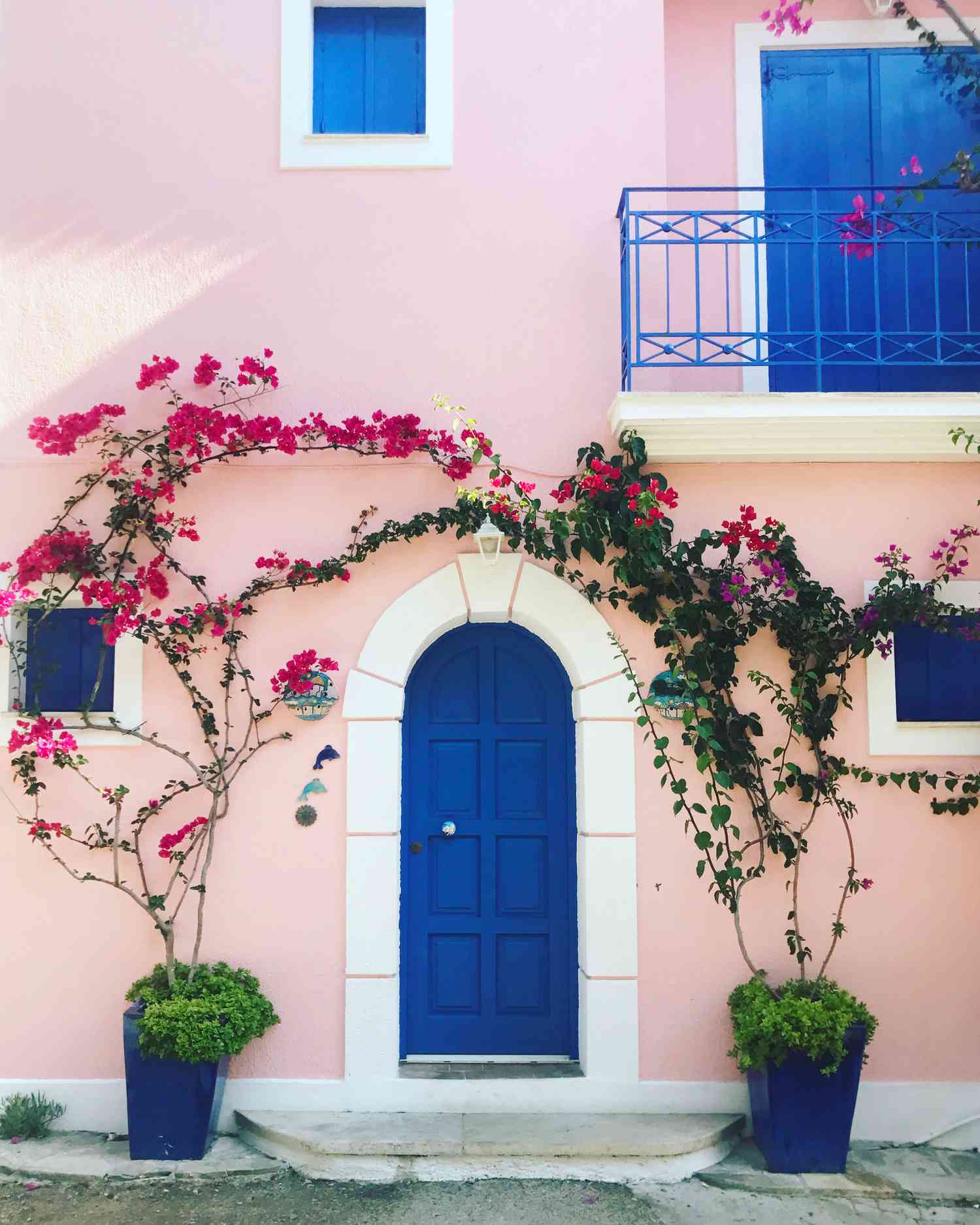 Una casa rosa con puerta azul en Grecia