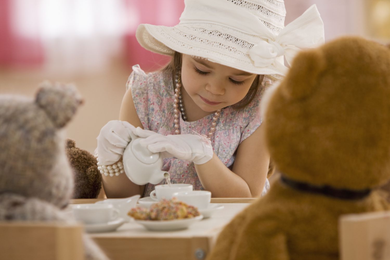 Mixed race girl having tea party with stuffed animals