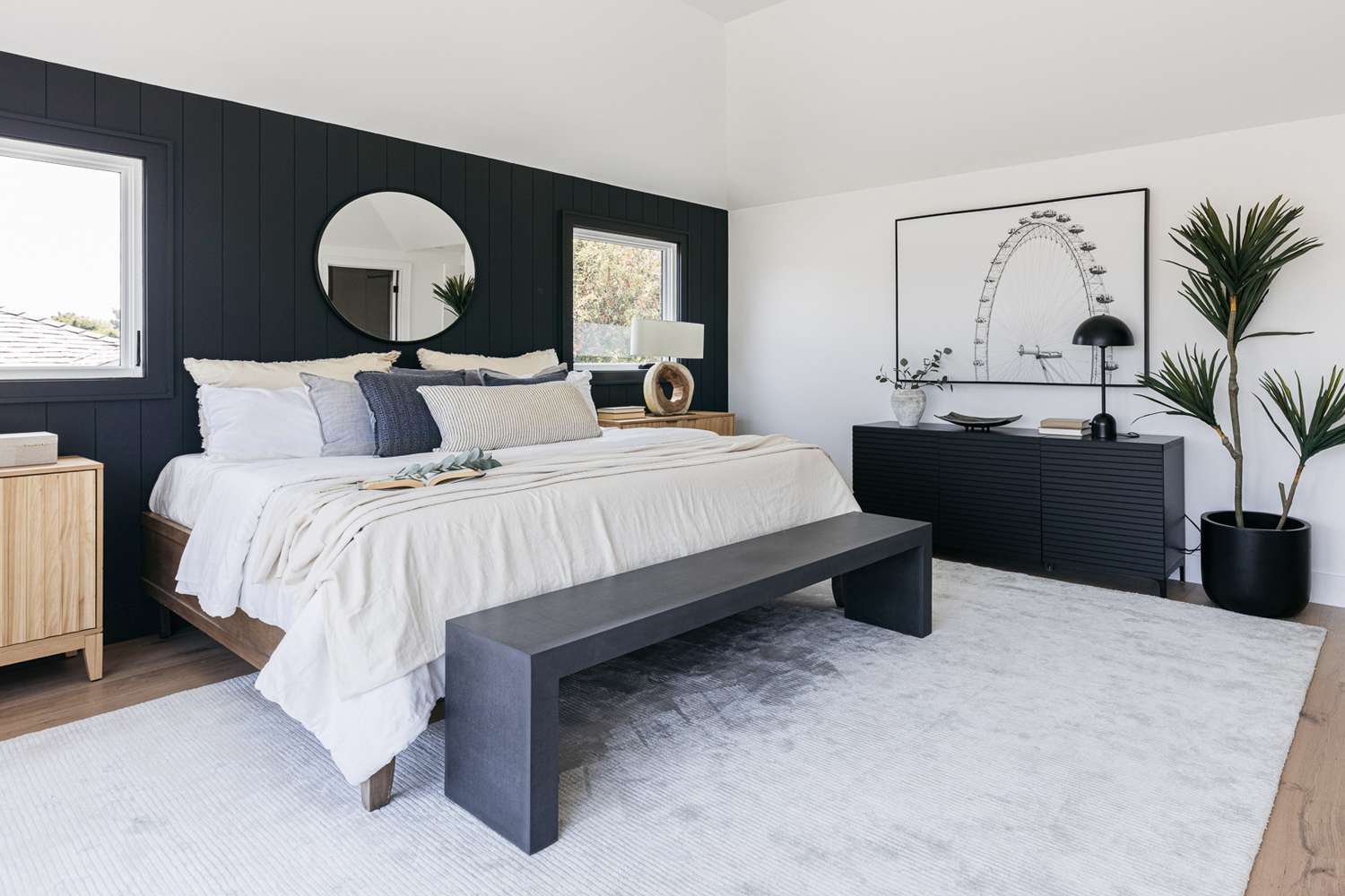 Dekoriertes Schlafzimmer mit marineblauen Wänden, Kommode und Bank um ein weißes Bett