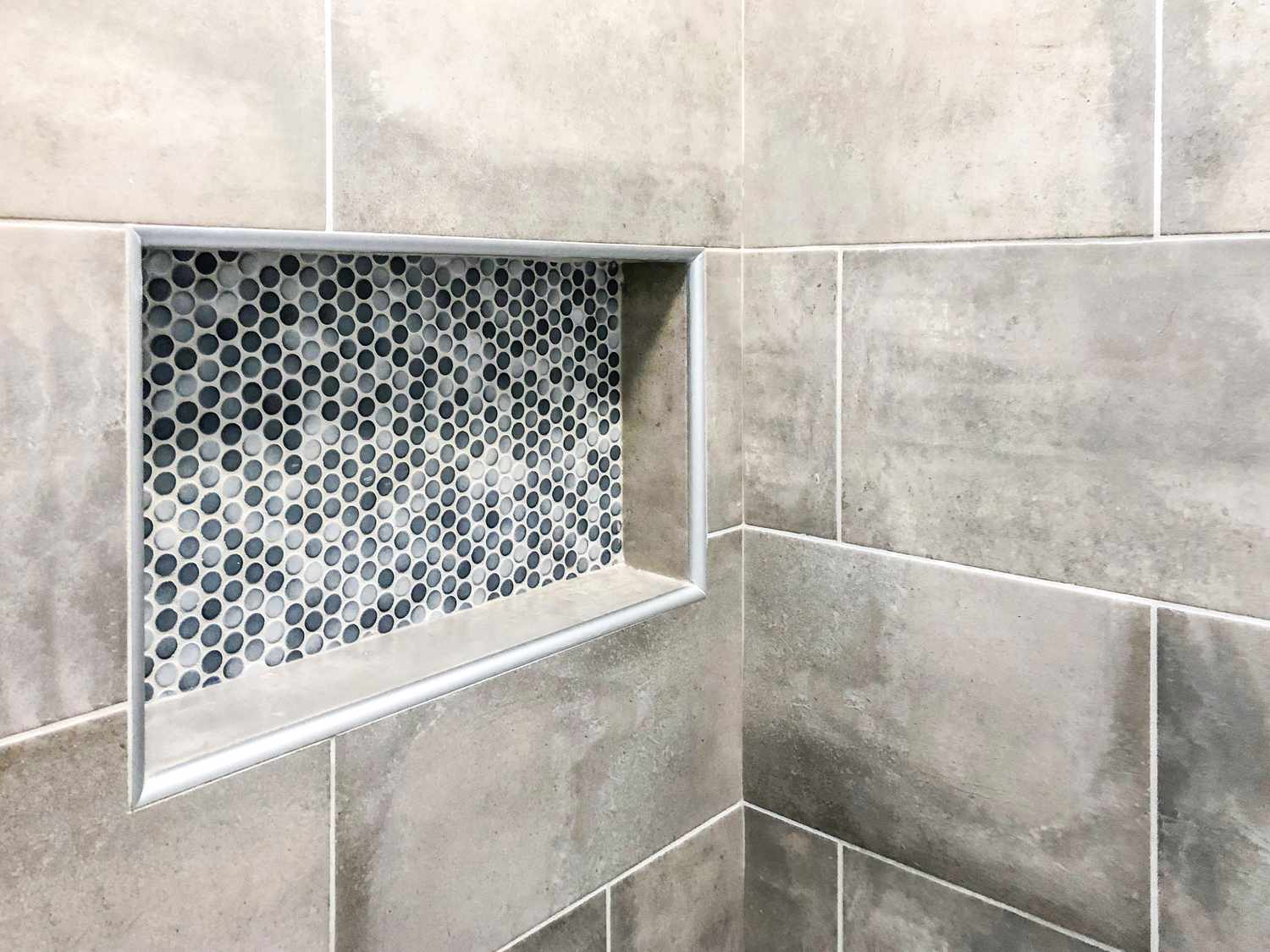 Parede de banheiro moderno em porcelanato no tom cinza com nicho decorativo personalizado retangular na parede para xampu e sabonete