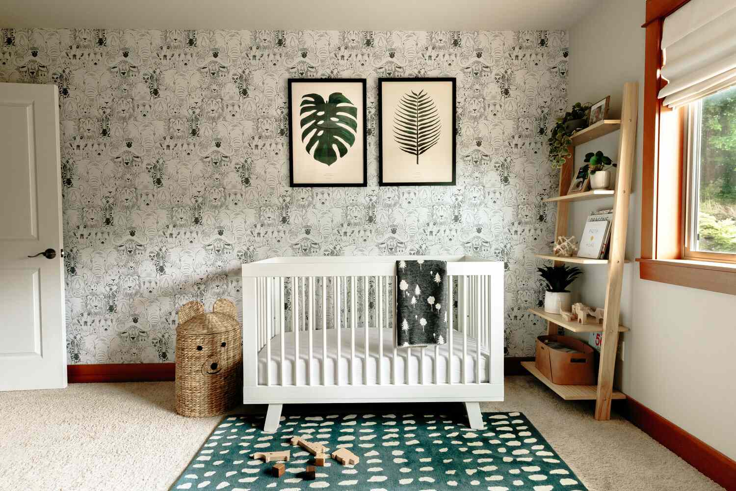 white crib in room with pattern wallpaper, leaf artwork on wall