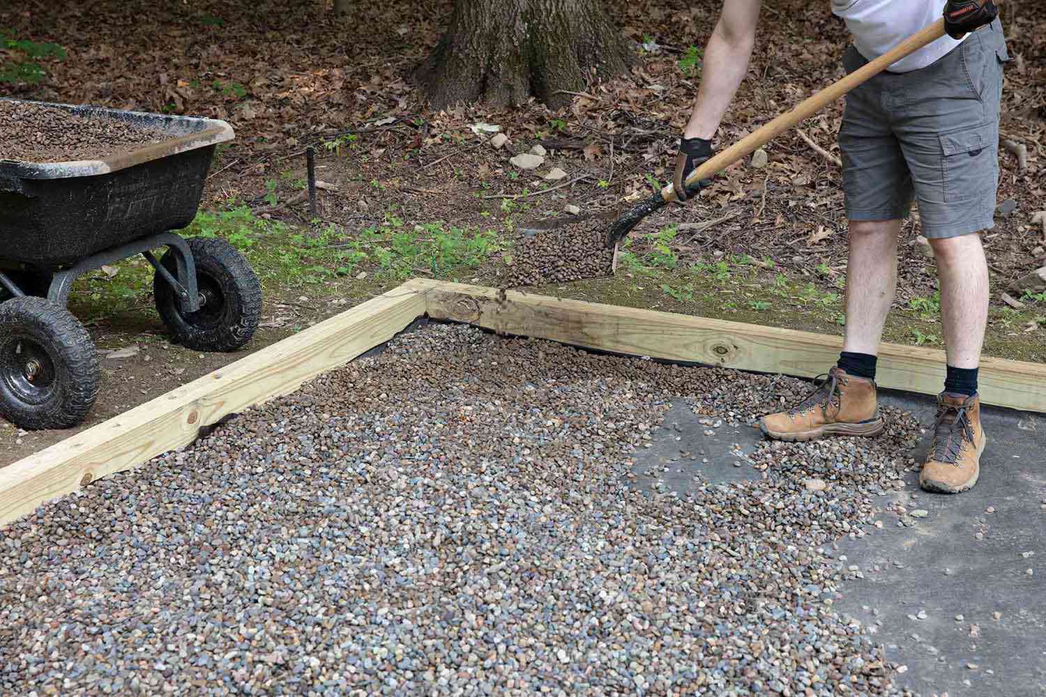 Erbsenkies, der über das Landschaftsgewebe innerhalb des Holzrahmens gelegt wurde