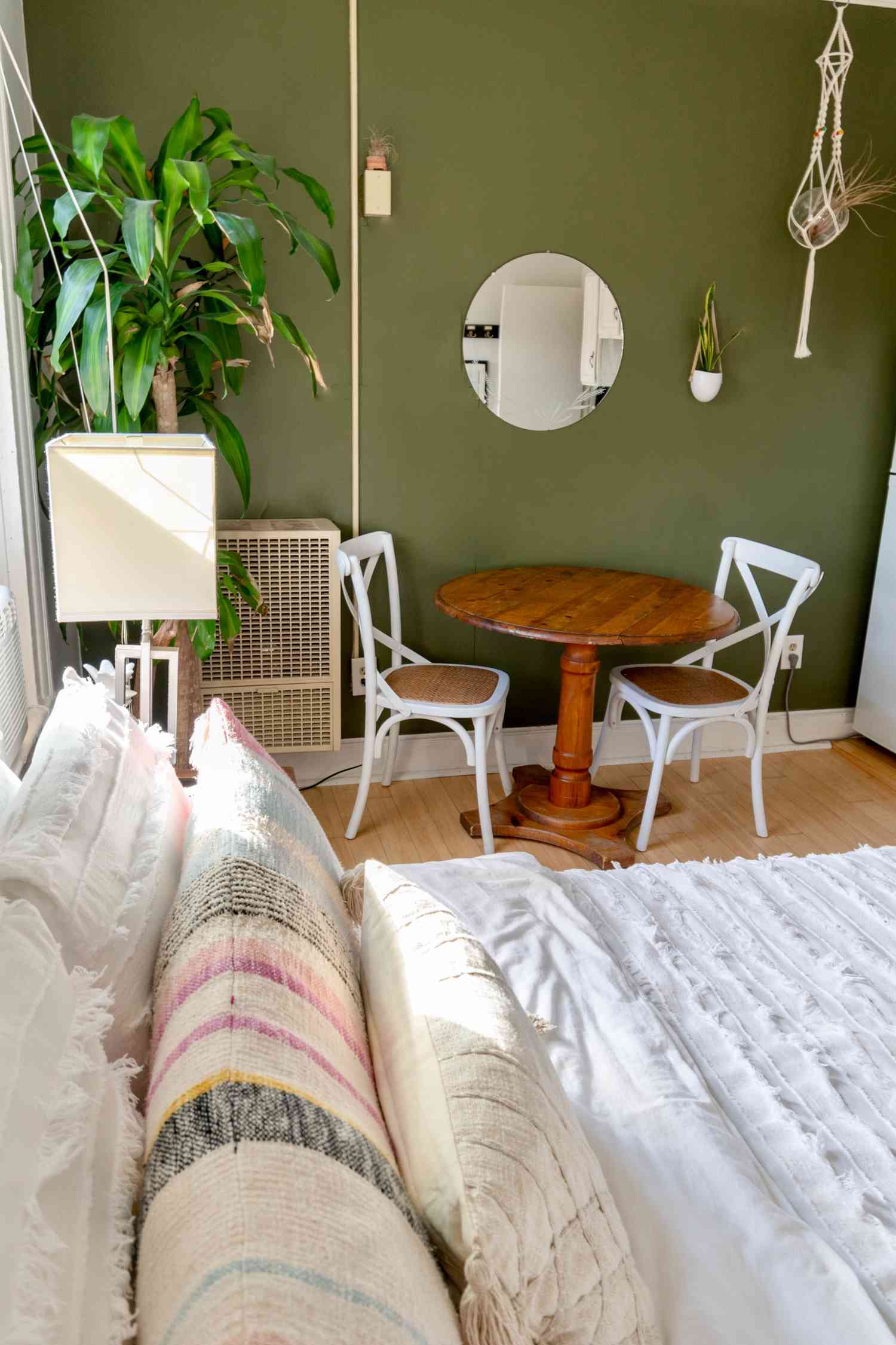 petit coin table à manger avec miroir, mur vert et plantes