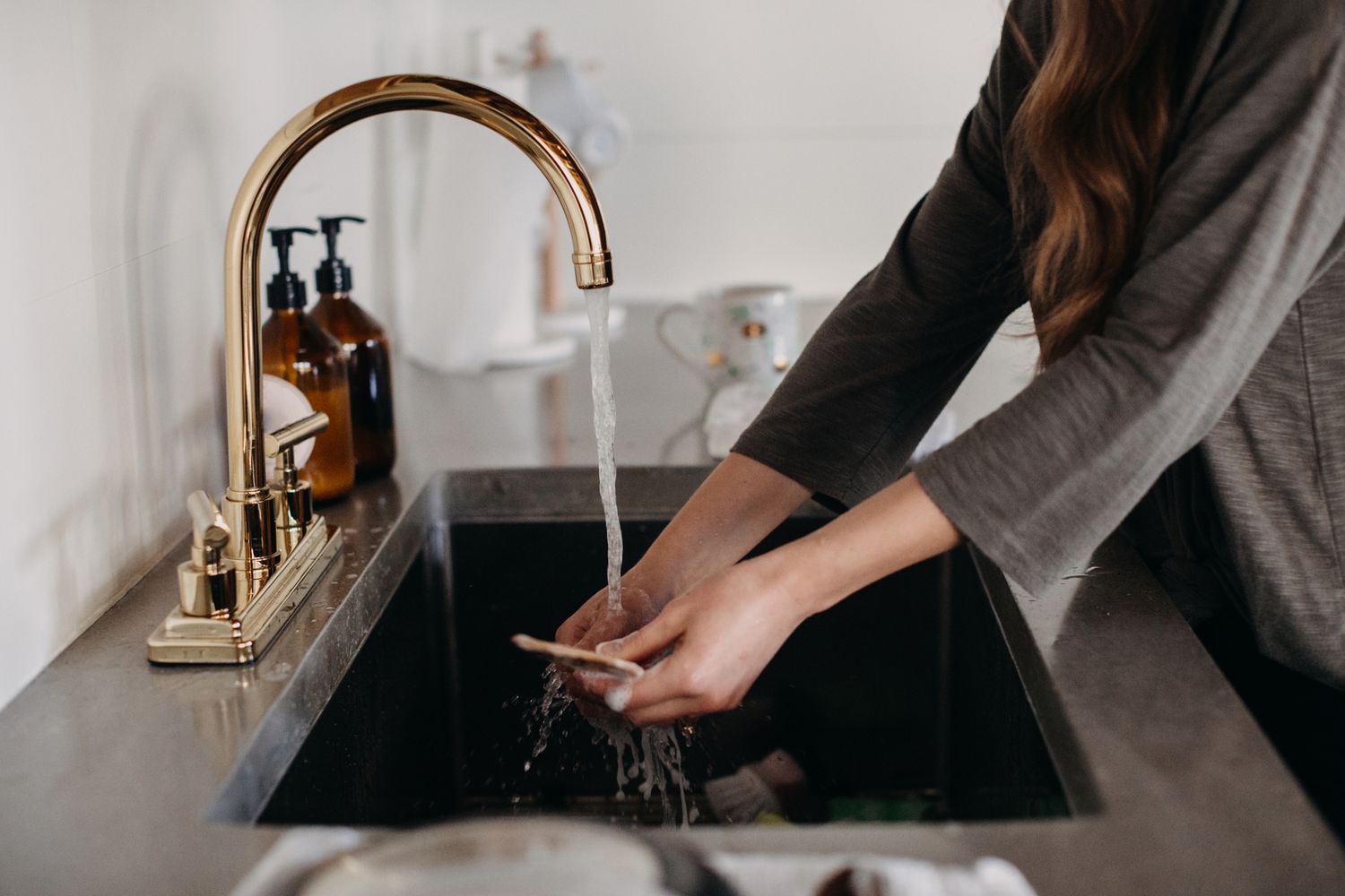 person rinsing something in the sink