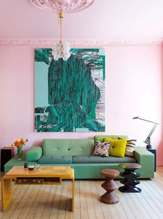 Sala rosa com uma grande obra de arte verde pendurada acima do sofá verde.