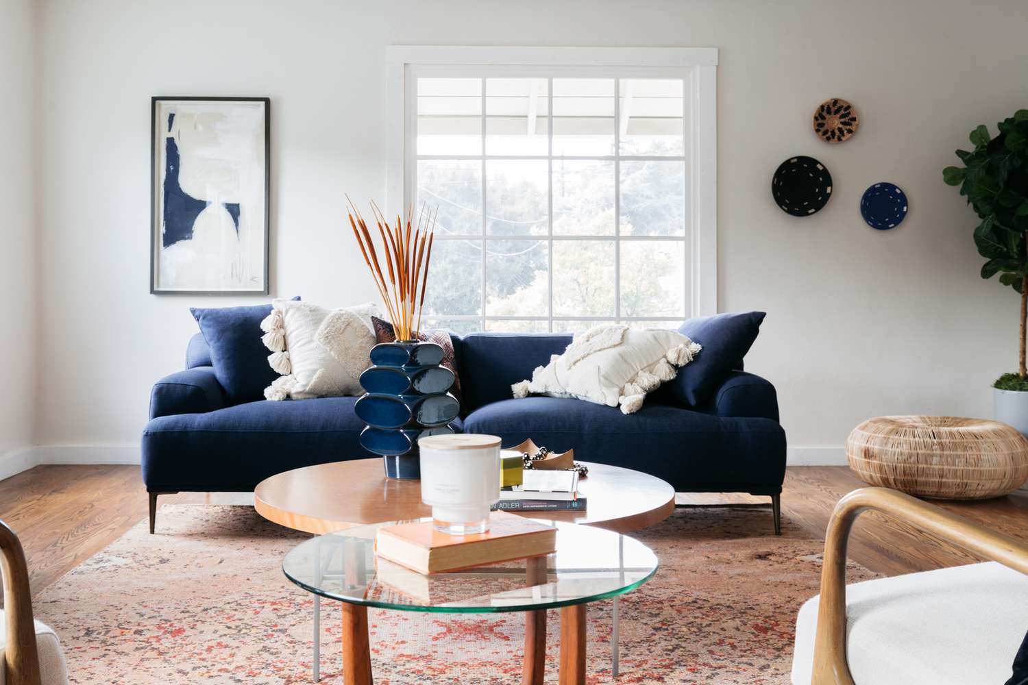 Sofá azul-marinho e decoração na sala de estar com mesas de centro de madeira e vidro