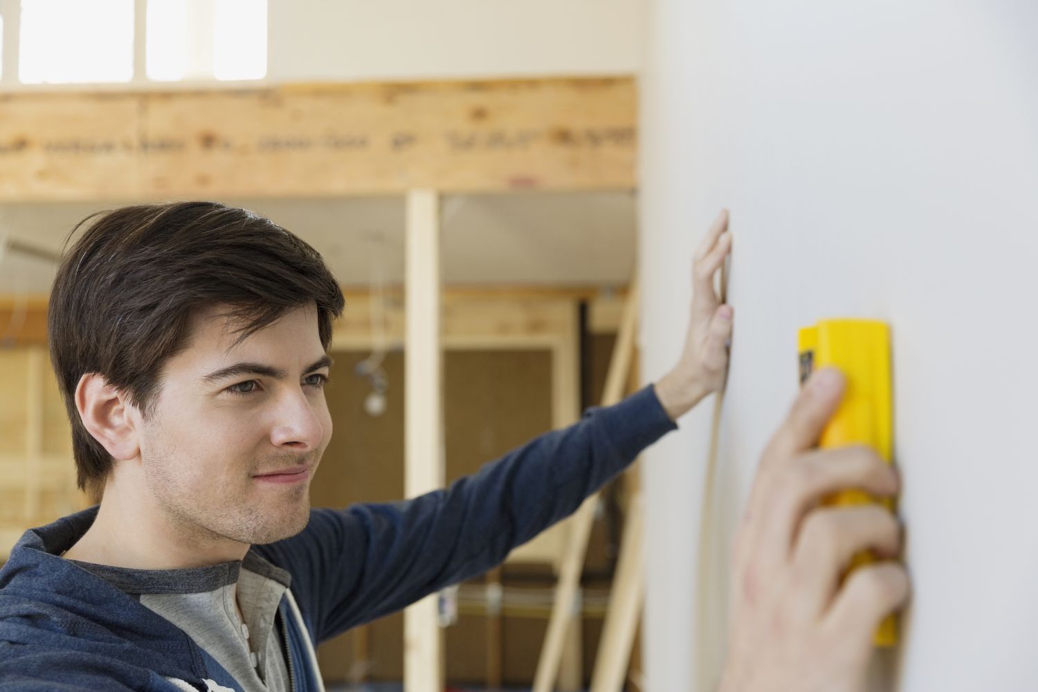 Junger Mann mit Bolzenfinder bei der Prüfung der Wand zu Hause