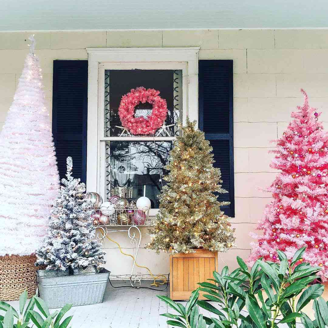 Eine mit verschiedenfarbigen künstlichen Weihnachtsbäumen geschmückte Veranda