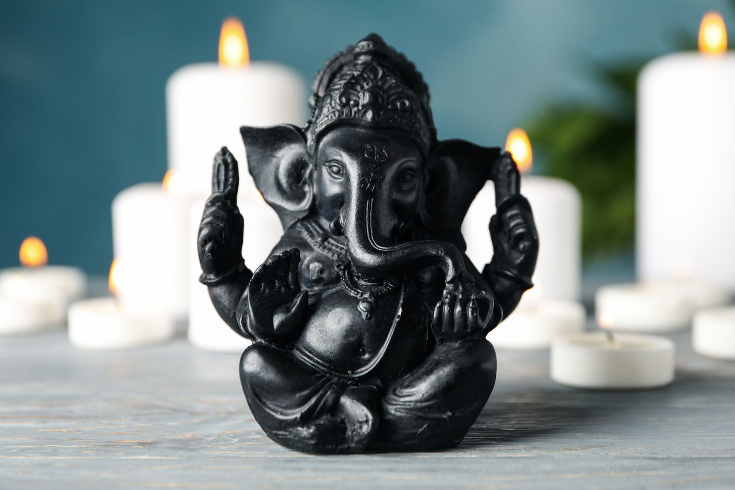Hindu-Gott Ganesha auf weißem Holztisch. Kerzen im Hintergrund