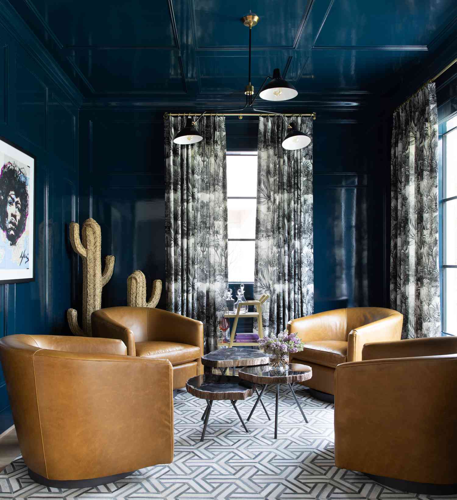 sala de estar com quatro cadeiras de couro, paredes azuis, mesas de centro com tronco de árvore