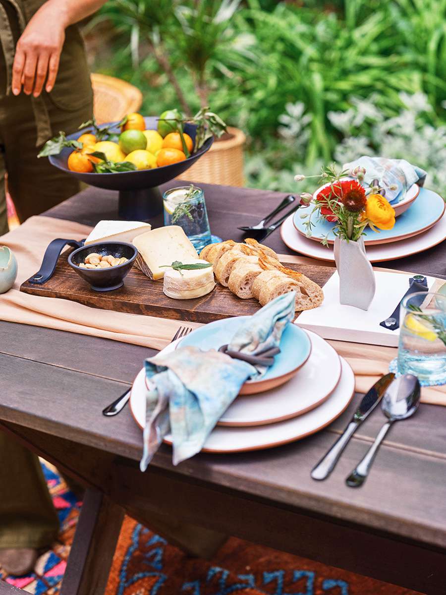 ein Serviertablett aus Holz und Marmor steht auf einem Holztisch mit Brot, Käse und Mandeln