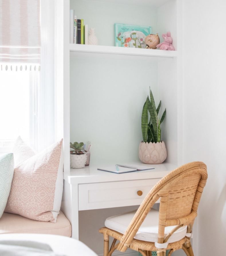 Bureau encastré étroit dans la chambre avec chaise de bureau en rotin.