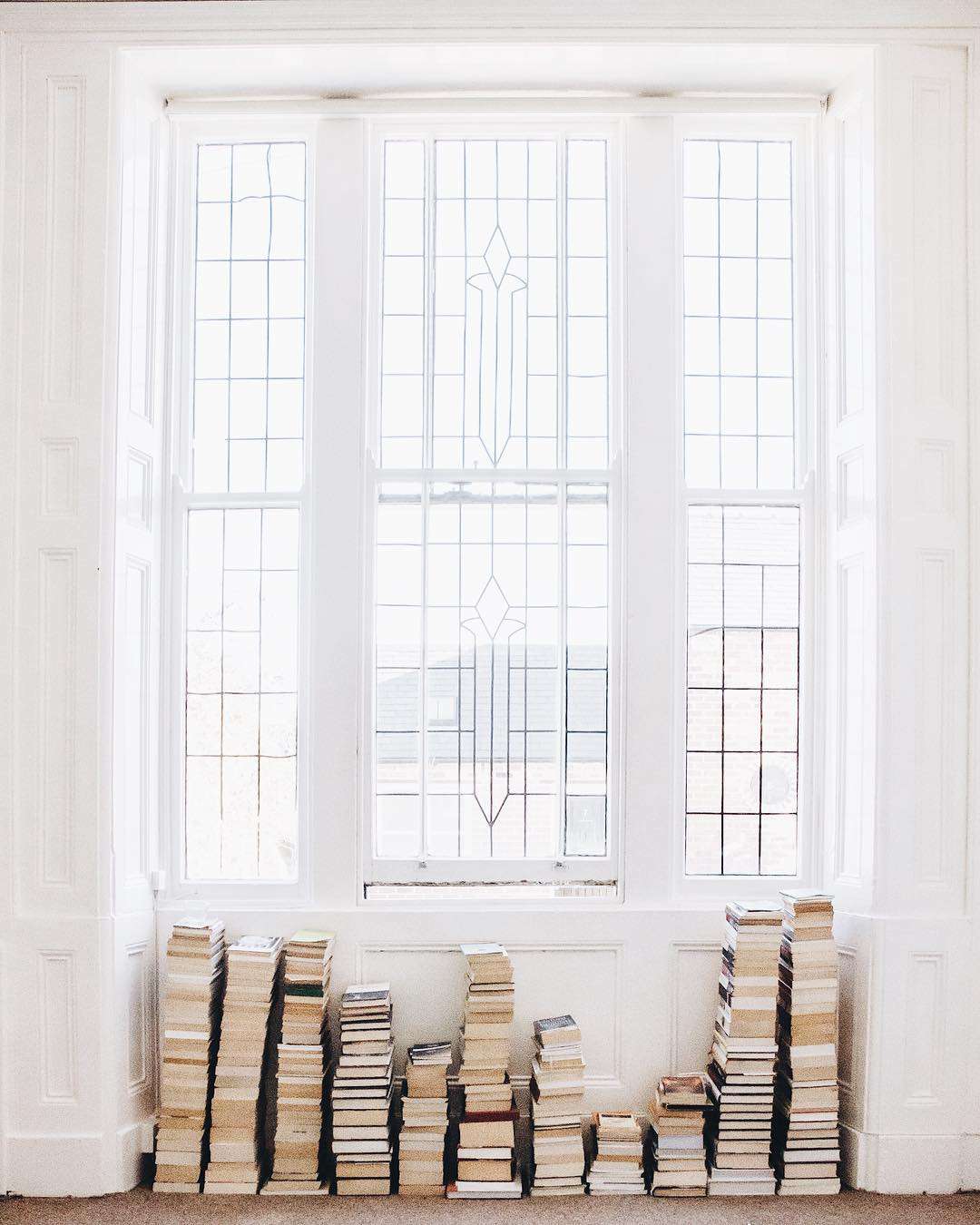 Pilhas de livros empilhados sob a janela