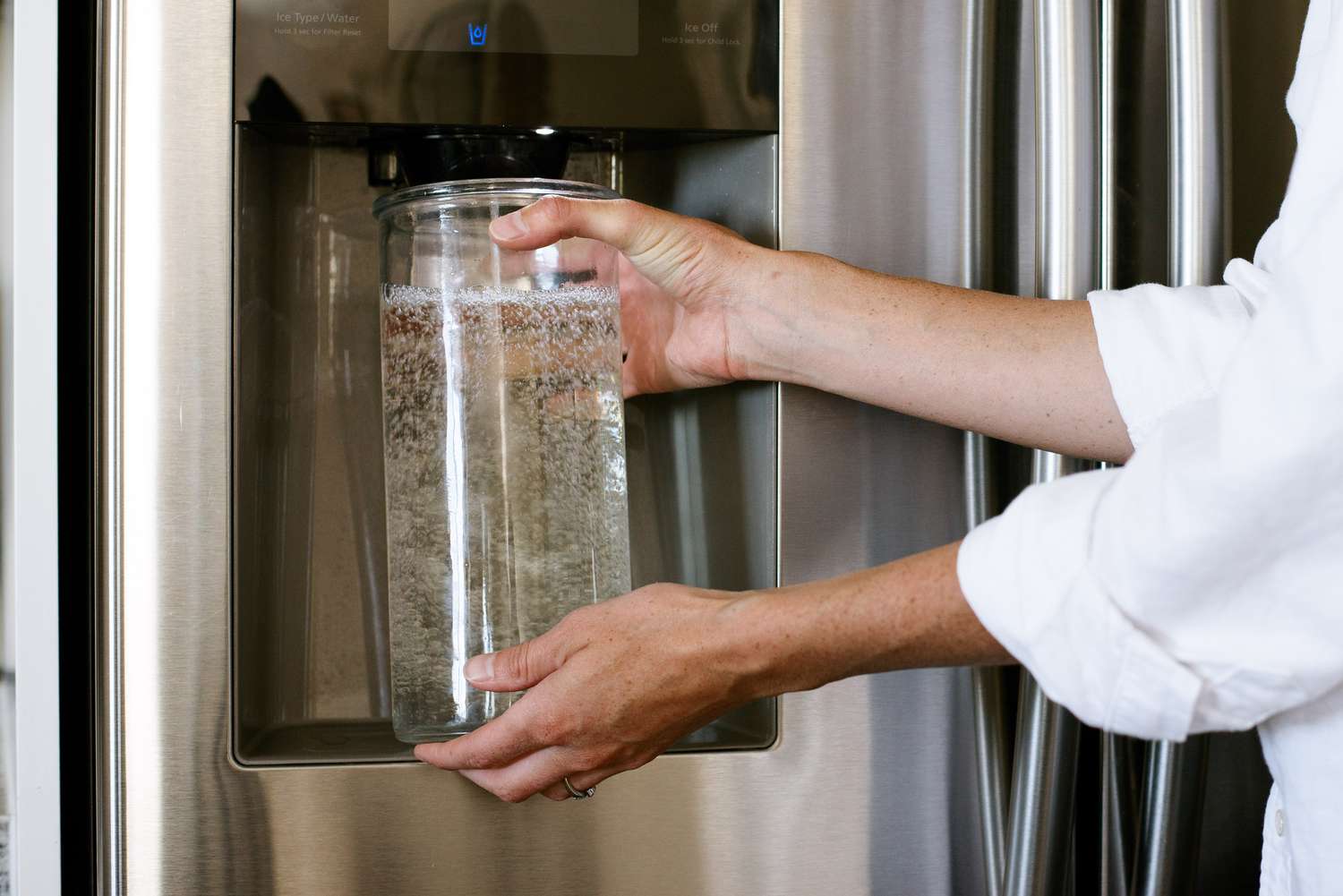 Filtro de agua nuevo en el frigorífico siendo enjuagado en una jarra separada