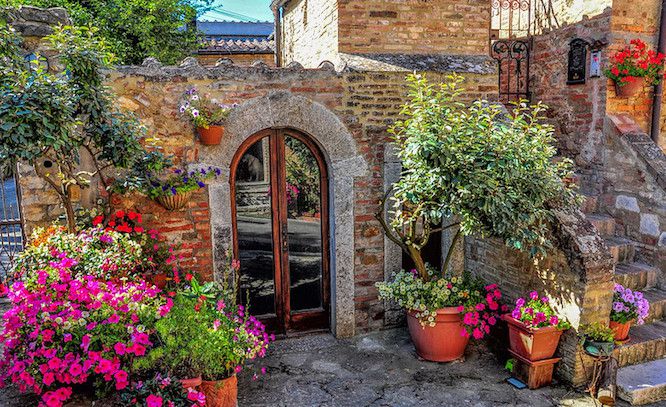 Steintor einer Villa mit bunten Blumen in Pflanzkübeln in der Toskana