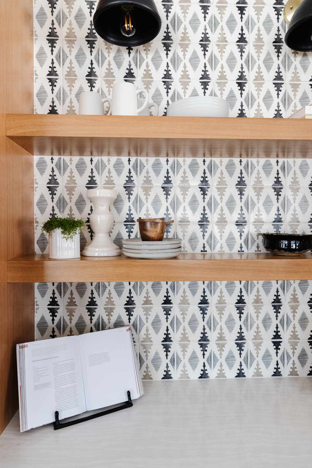 kitchen counter with floating shelves and backsplash, one cookbook propped open for display