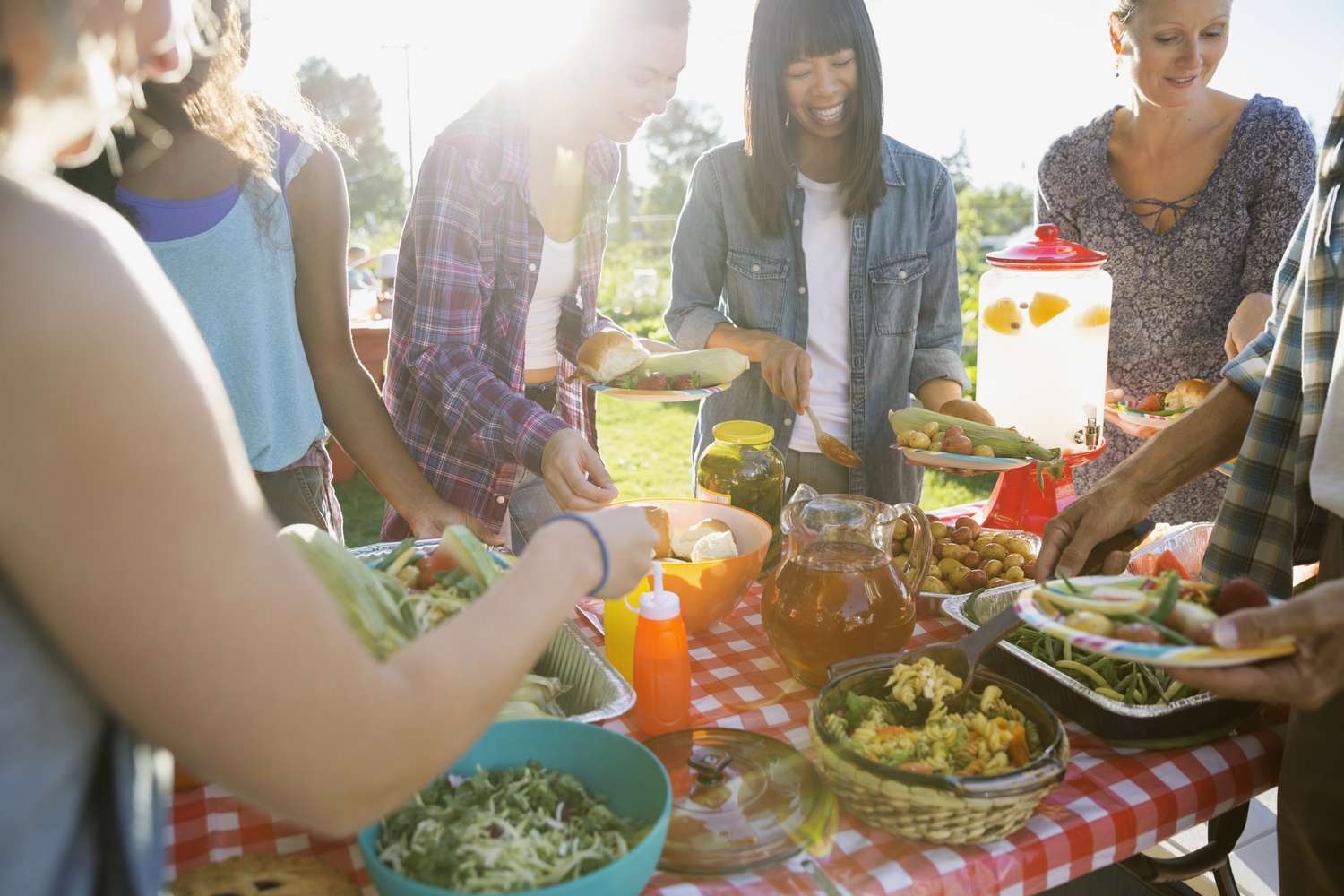 Lächelnde Nachbarn am Potluck-Tisch im sonnigen Park