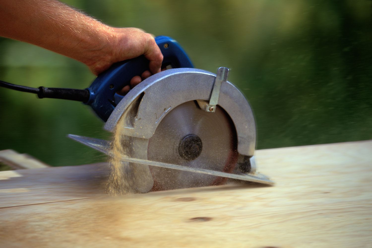 Homem cortando madeira com serra circular, foco na serra (movimento desfocado)