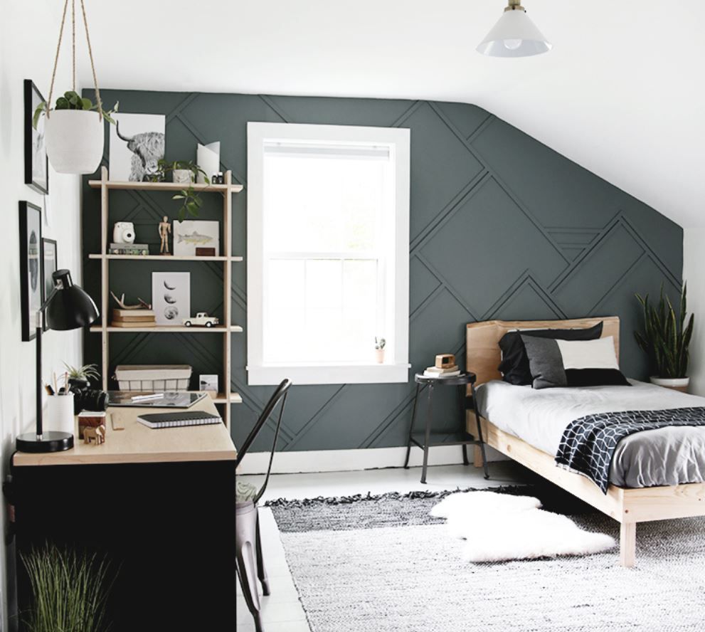 Chambre d'adolescent avec mur à panneaux géométriques en vert foncé et touches rustiques de ferme.