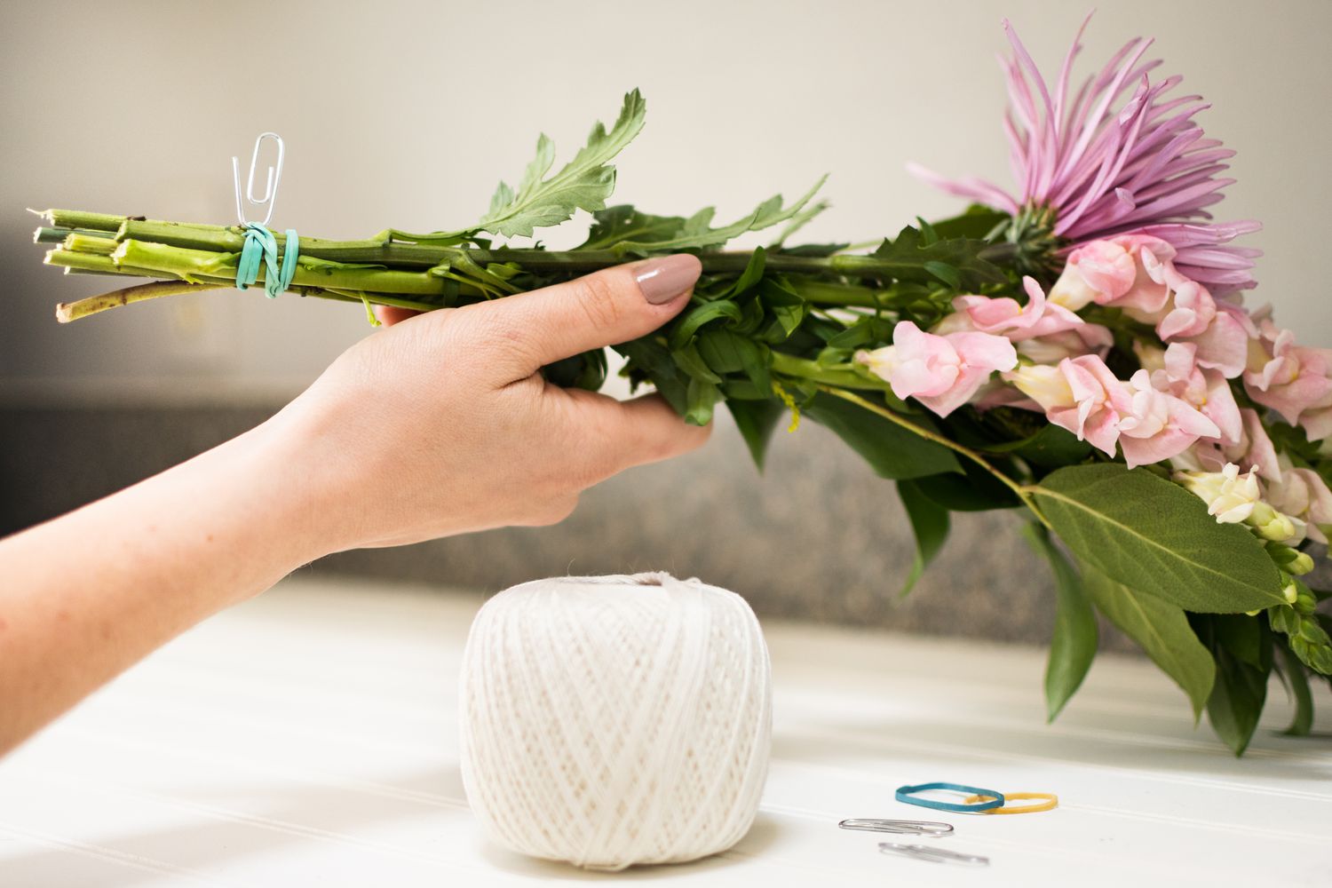 Blumen mit einem Gummiband und einer Büroklammer zum Aufhängen zusammengetragen