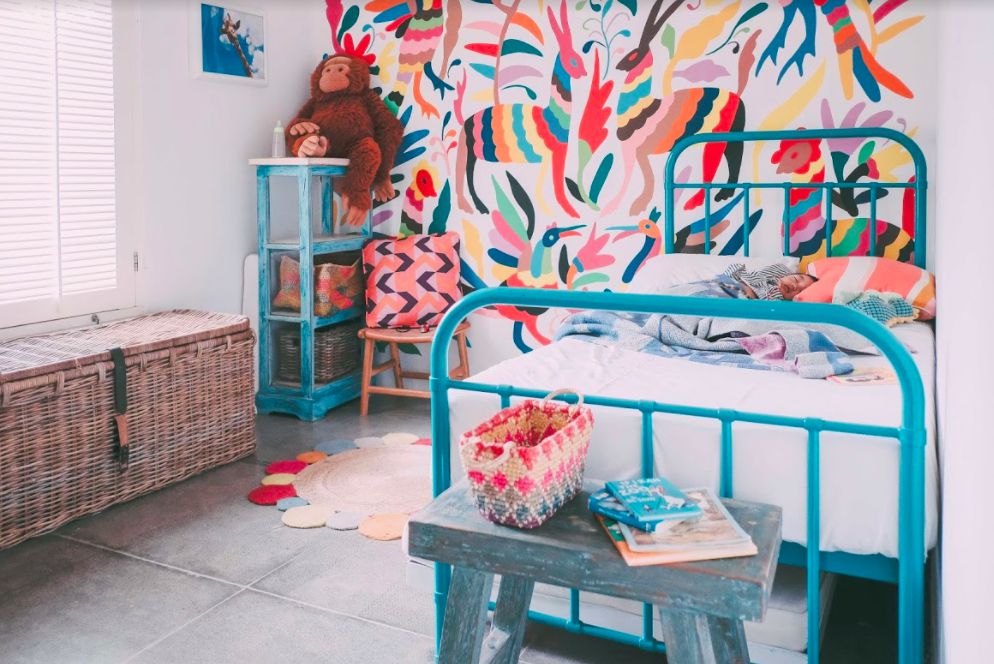 Cama em um quarto de criança muito colorido com papel de parede colorido