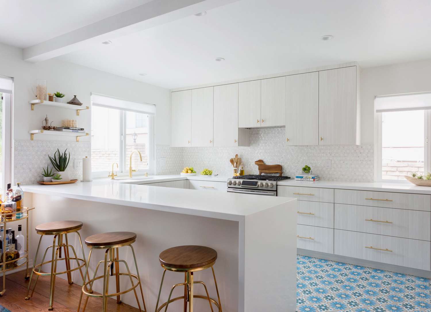 Thasso-Marmor-Küchenrückwand in einer komplett weißen Küche mit blauen Bodenfliesen