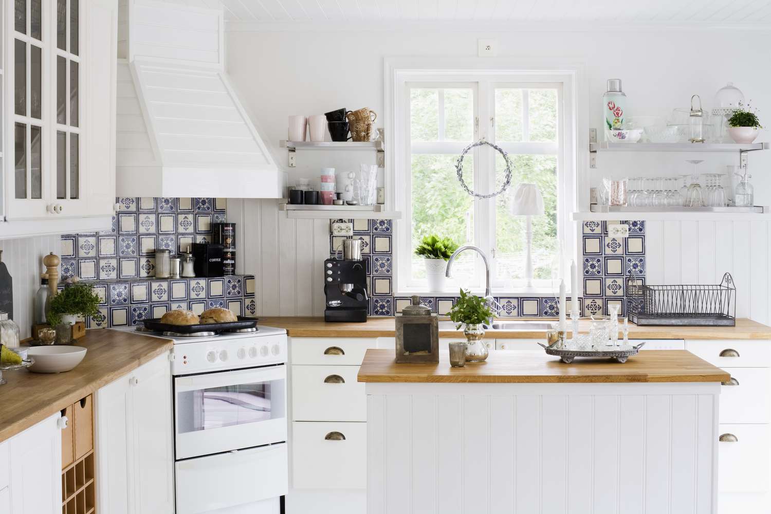 Une cuisine blanche avec des accents légers, en bois naturel et en carrelage bleu