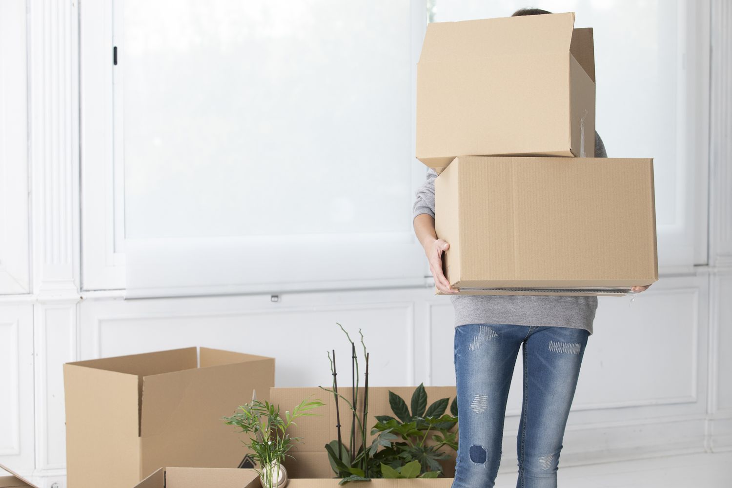 Unbekannte Frau trägt Kartons in die neue Wohnung