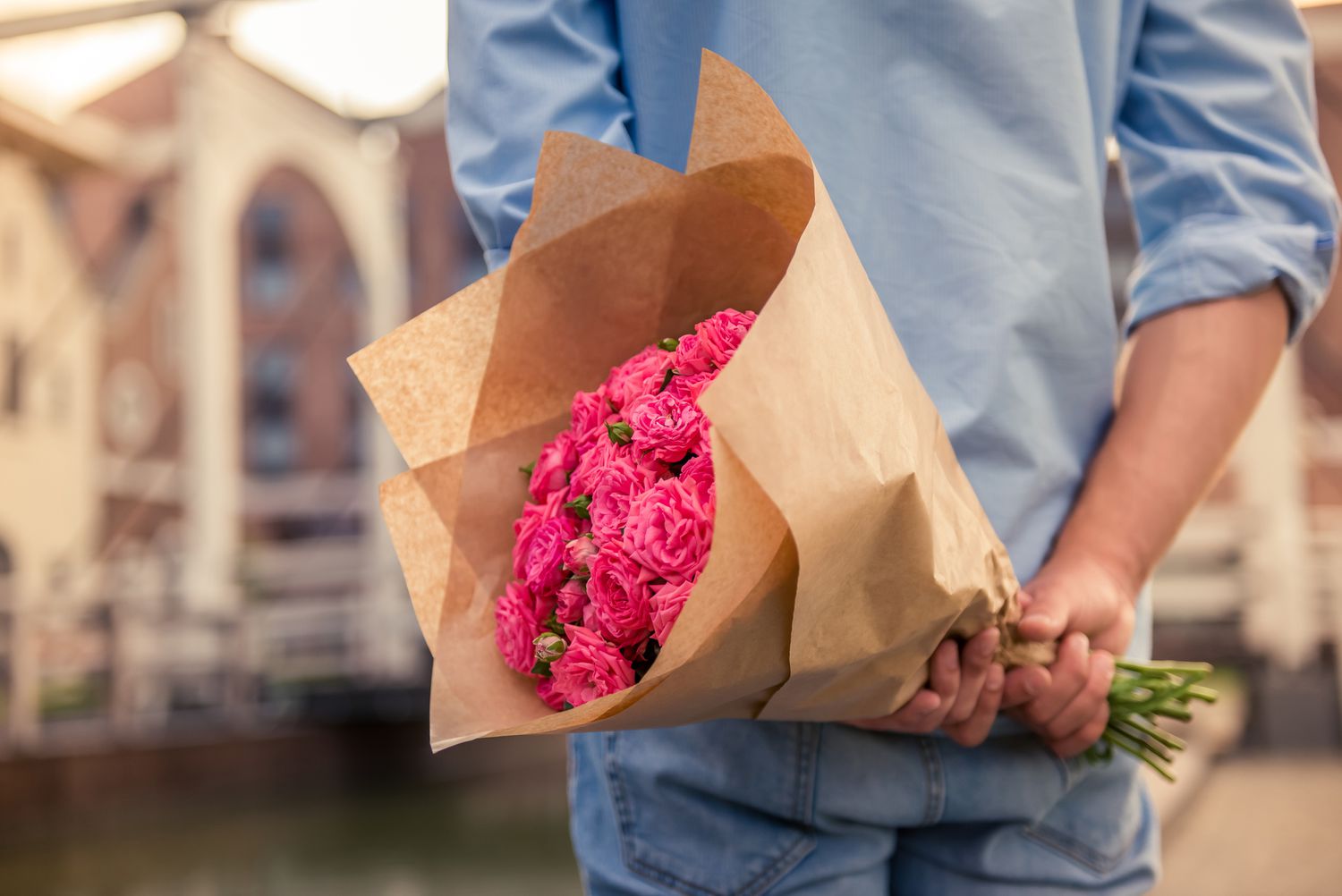 Junger Mann hält rosa Blumen