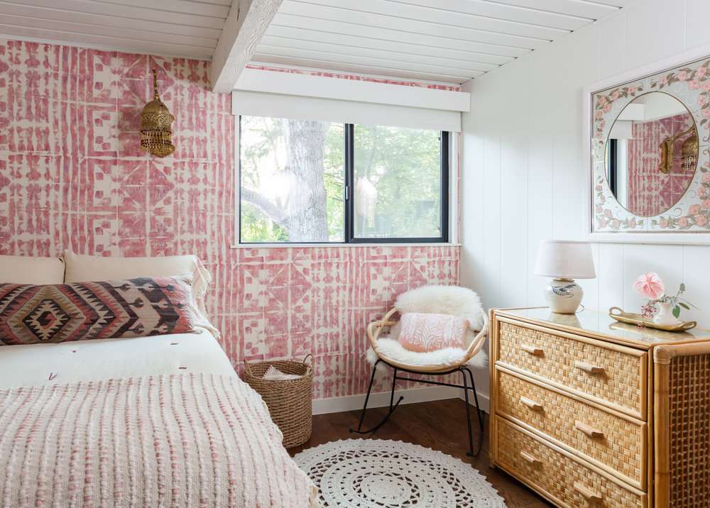 Jugendzimmer mit rosa gemusterter Tapete als Akzentwand.