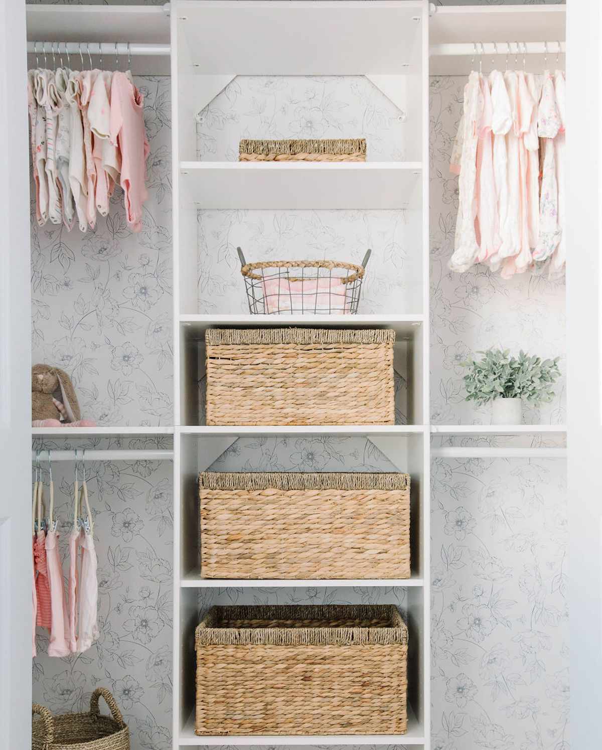 nursery closet with multiple rods to hang clothes and storage shelves with wicker baskets for others