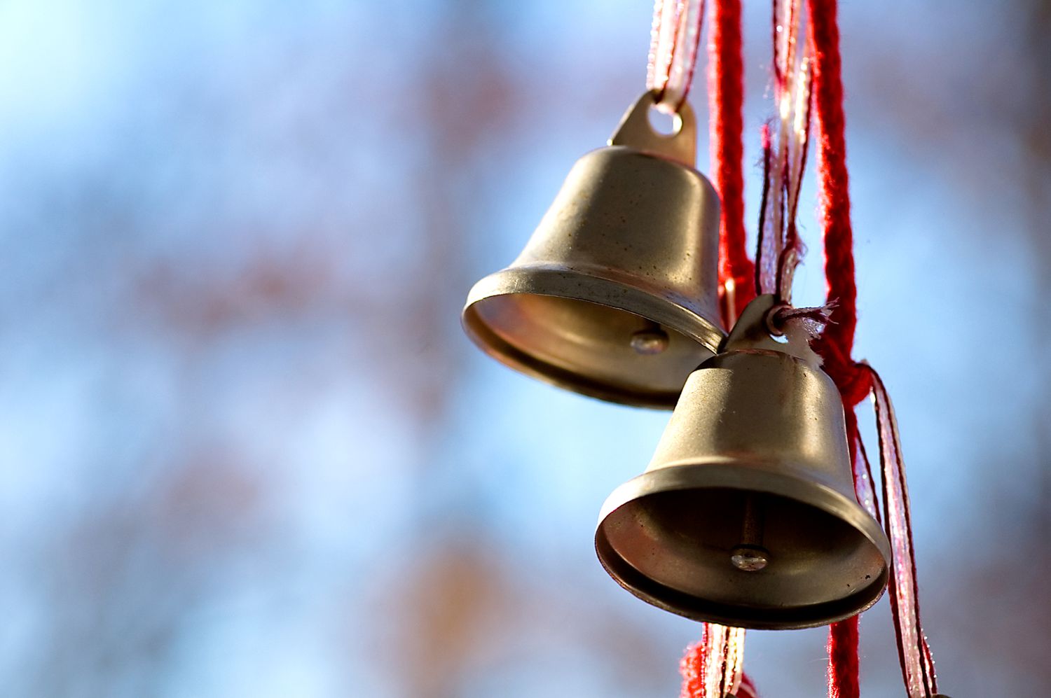two metal bells hanging on a red ribbon and cord