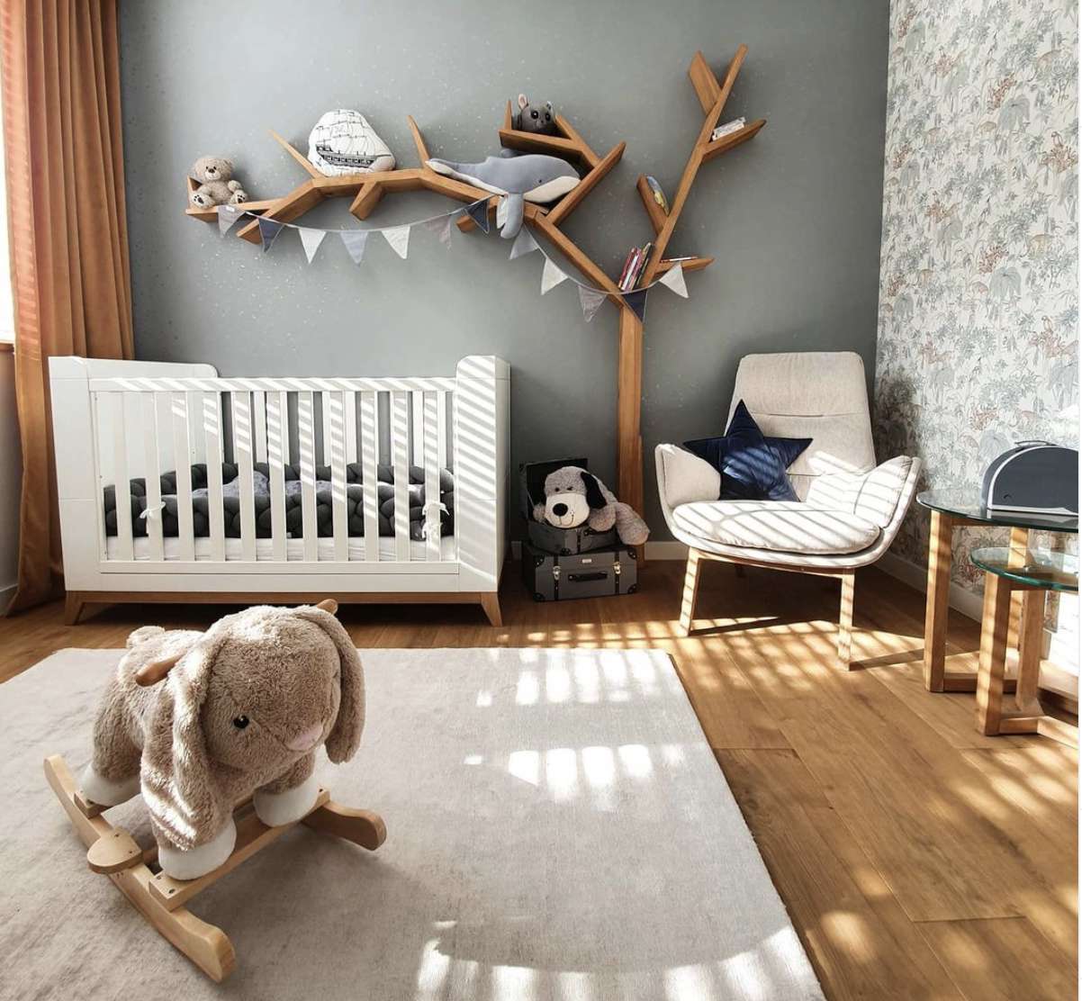 nursery with shelving shaped like a tree, gray walls, chair in corner, white crib