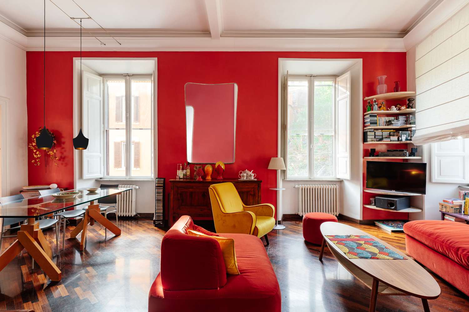 Luz natural enchendo o cômodo pintado de vermelho com duas janelas