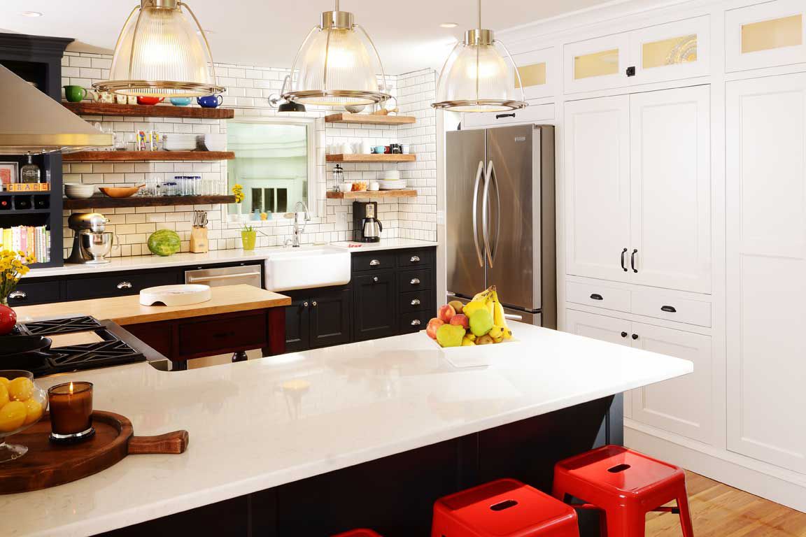  Küche mit schwarzen Schränken und weißer Schürzenspüle, akzentuiert mit roten Hockern