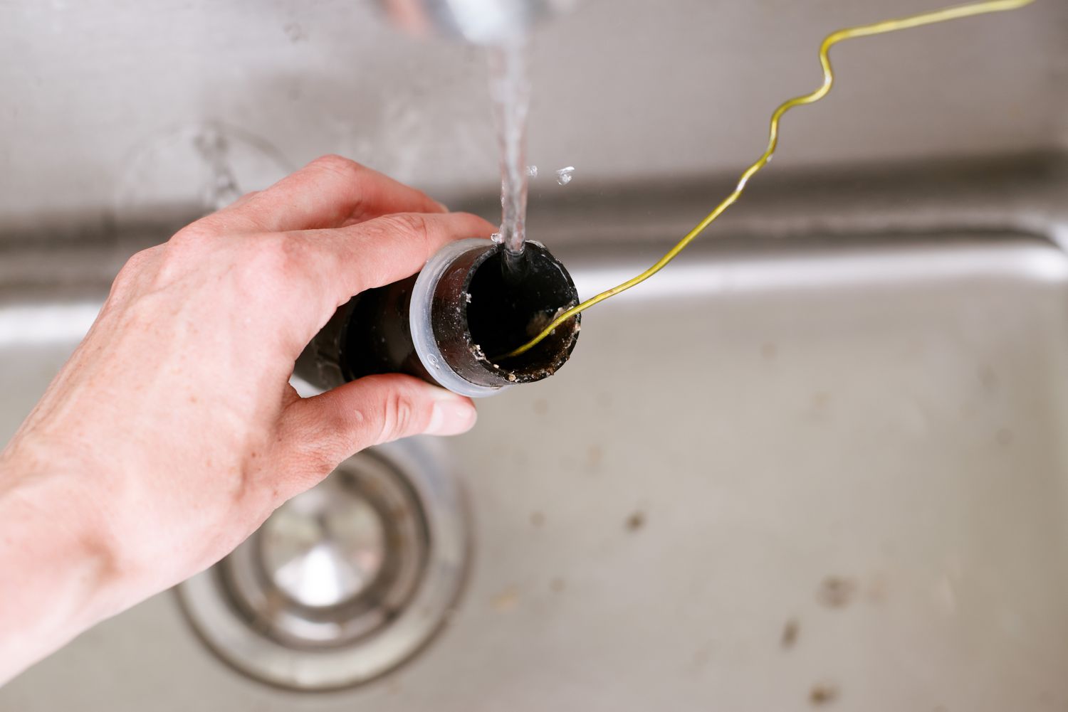 Trap arm in sink garbage disposal checked with yellow wire for clogs