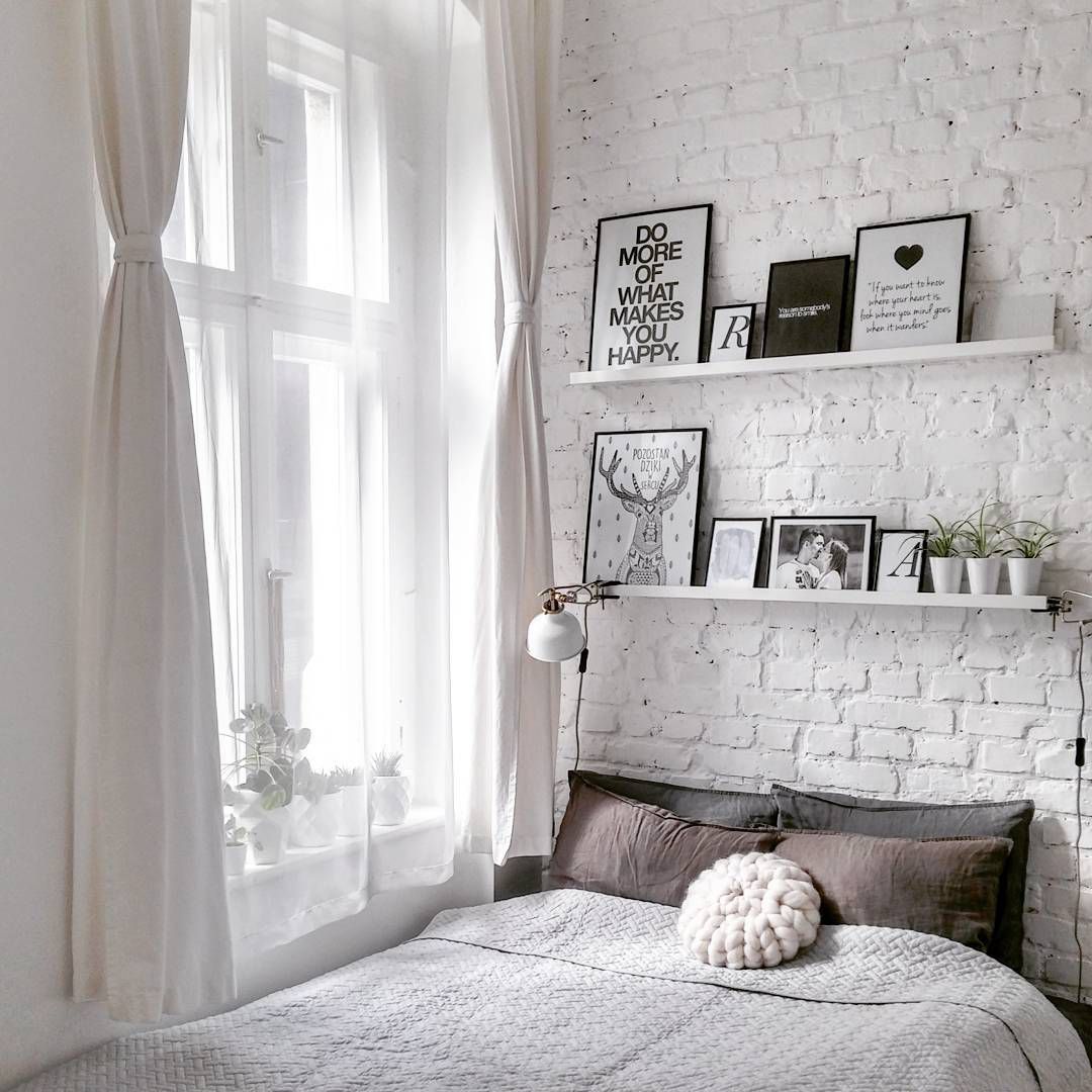 Um quarto com uma parede de tijolos brancos e prateleiras