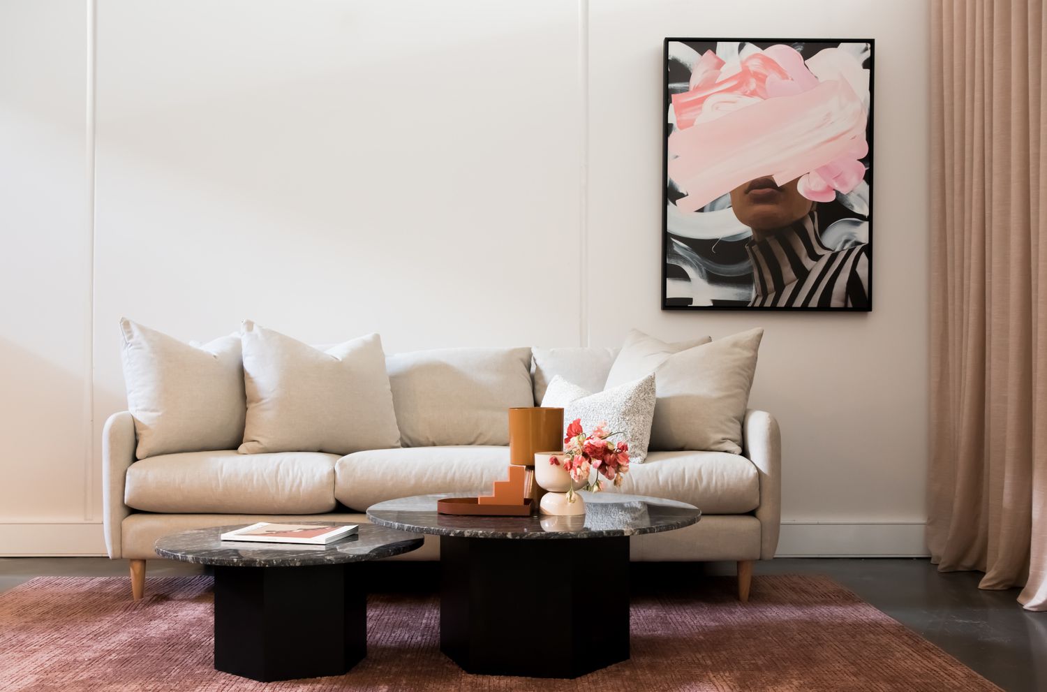 living room with white sofa, pink rug, and black coffee tables