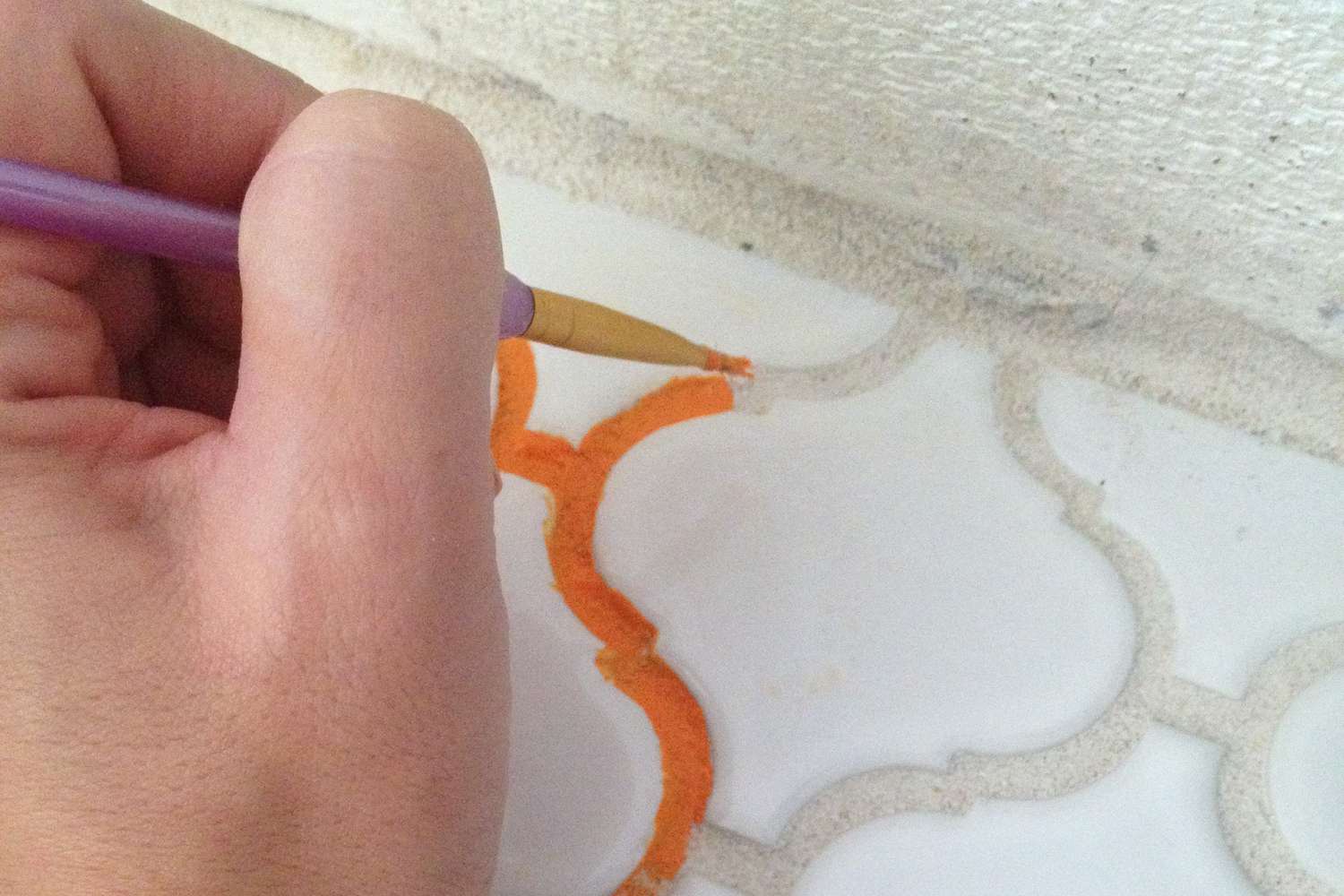 Orangene Fugenmasse von Hand mit feinem Pinsel streichen
