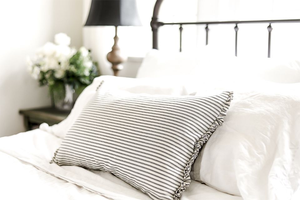 Ein gestreiftes Kissen auf einem weißen Bett