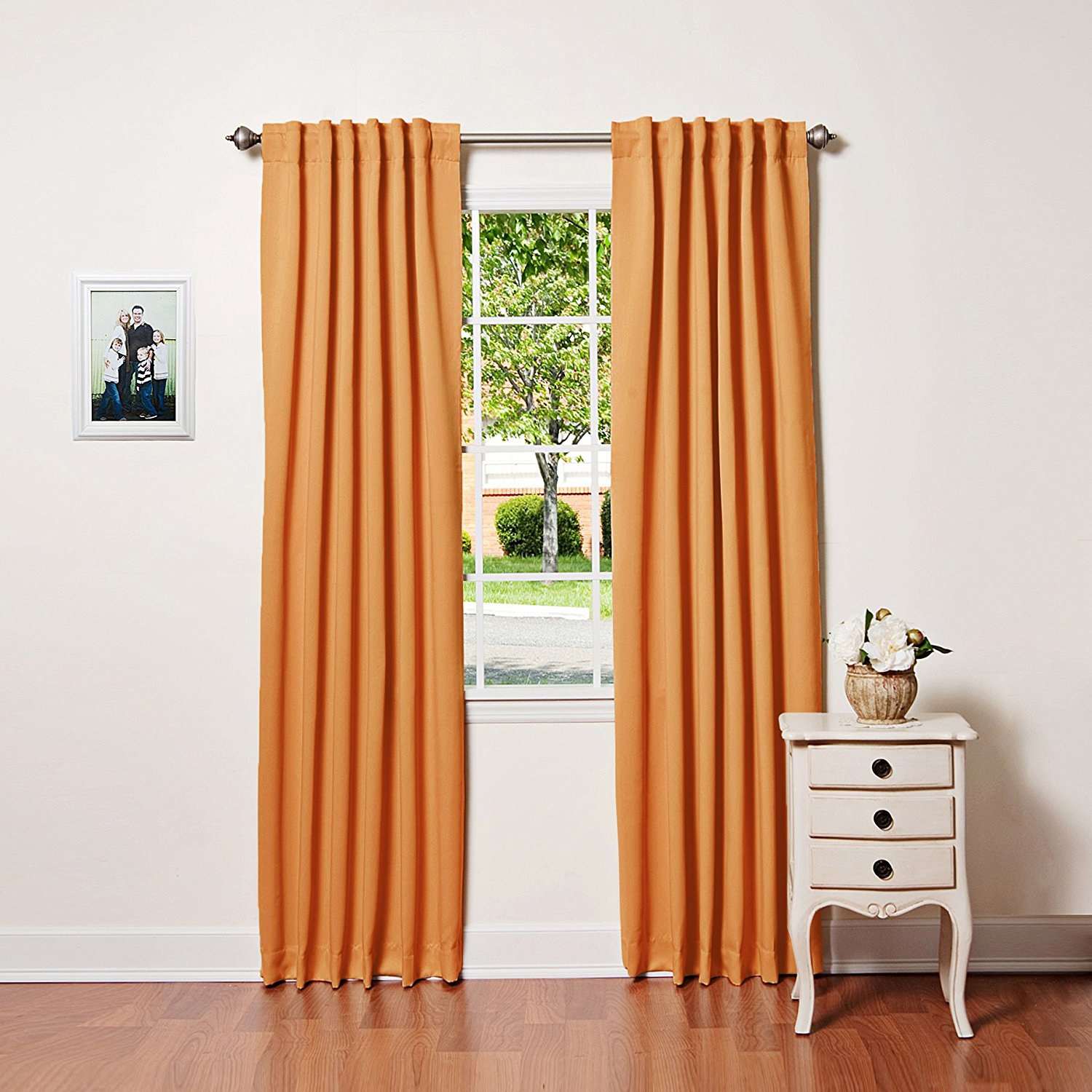 orange rod pocket drapes in white room in front of window