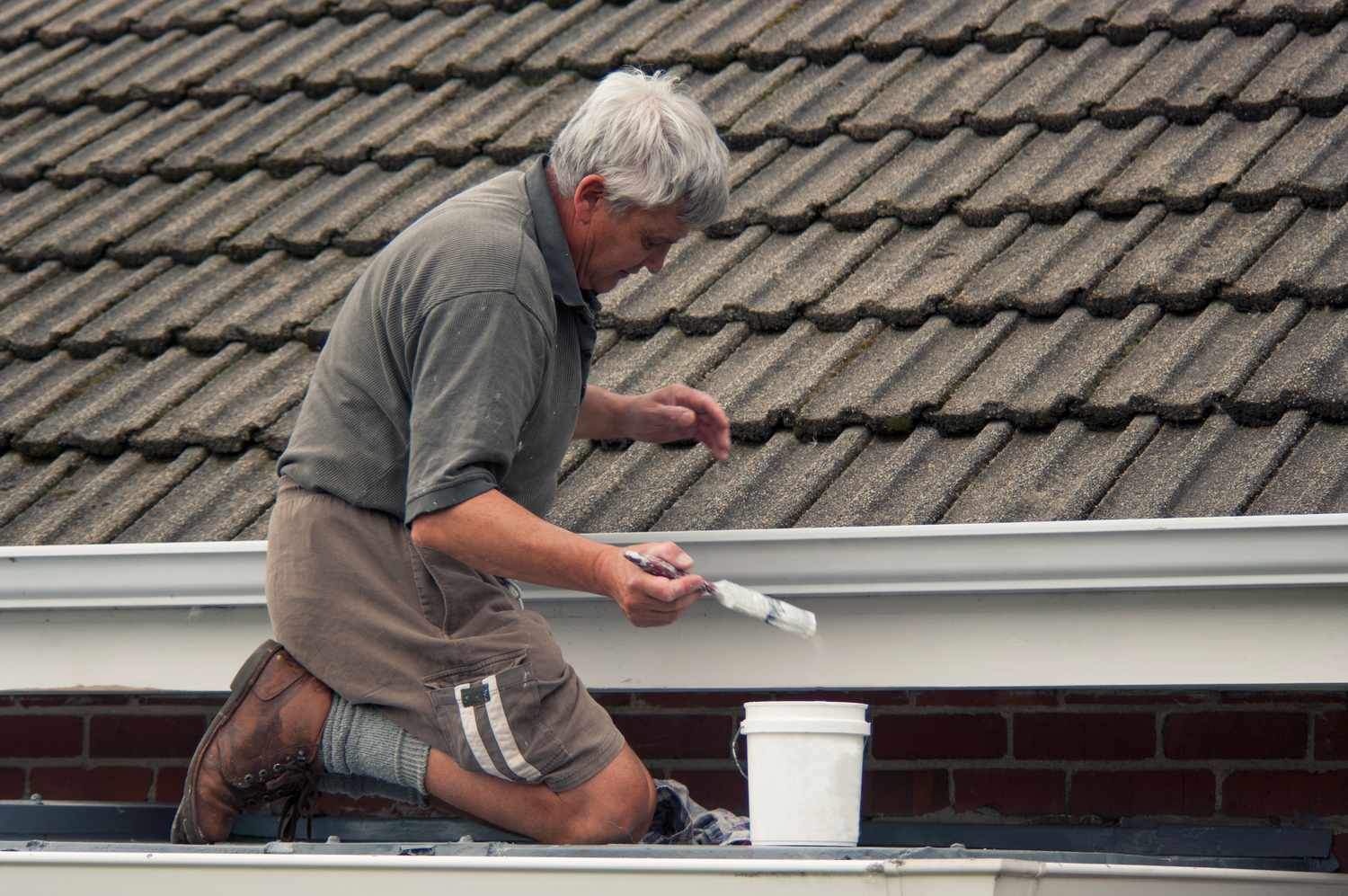 Ein Mann streicht ein Dach weiß